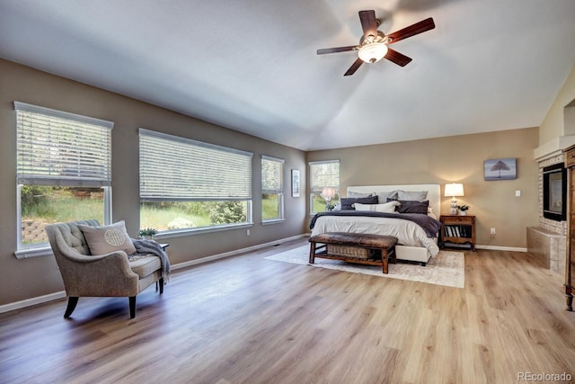 7329 Arco Iris Ln, Castle Pines, CO 80108 - bedroom featuring light wood-style flooring, lofted ceiling, ceiling fan, and a glass covered fireplace
