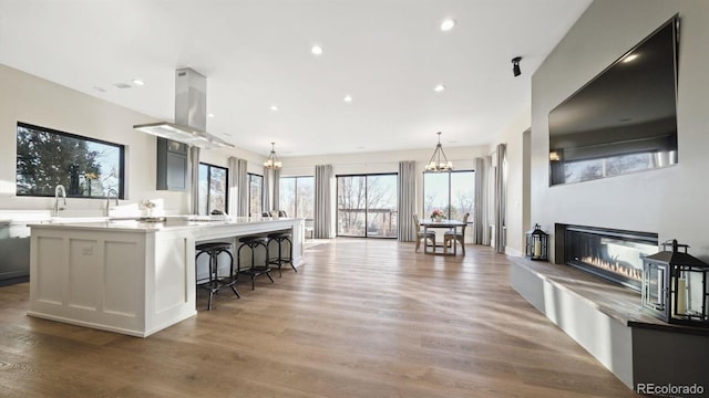 kitchen with decorative light fixtures, a kitchen breakfast bar, a large island, a chandelier, and hardwood / wood-style flooring