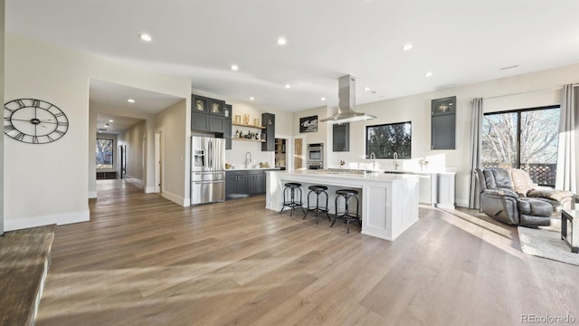 kitchen with a kitchen island, stainless steel appliances, sink, island range hood, and a breakfast bar