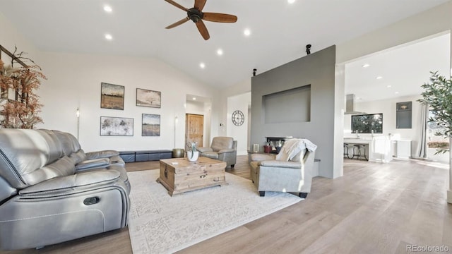 living room with ceiling fan, light hardwood / wood-style flooring, a fireplace, and lofted ceiling