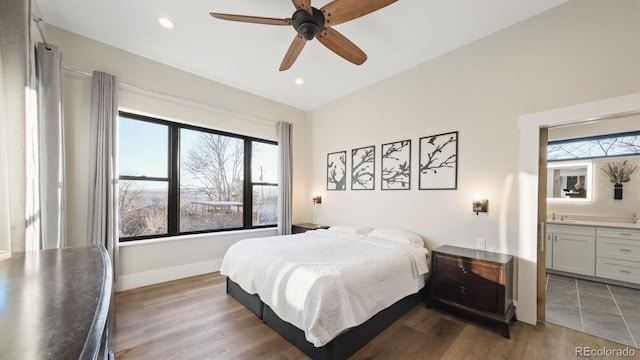 bedroom with ceiling fan, multiple windows, connected bathroom, and hardwood / wood-style flooring