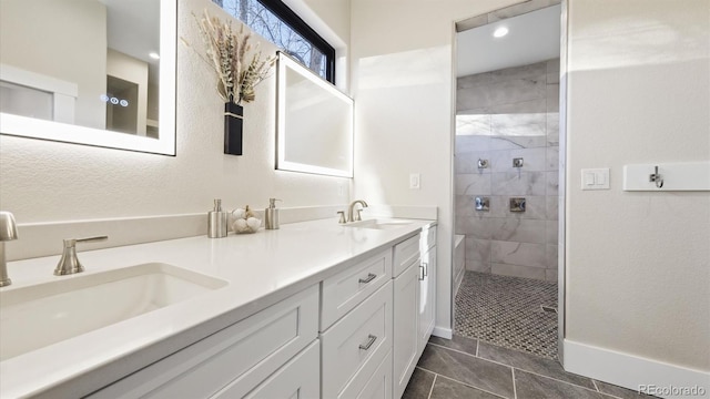 bathroom with tiled shower, vanity, and tile patterned flooring