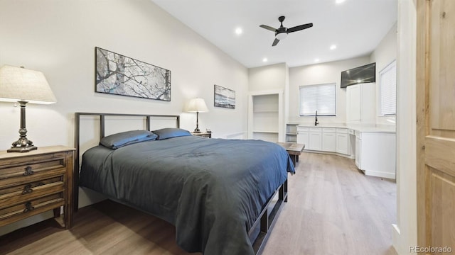 bedroom featuring ceiling fan, sink, and light hardwood / wood-style flooring