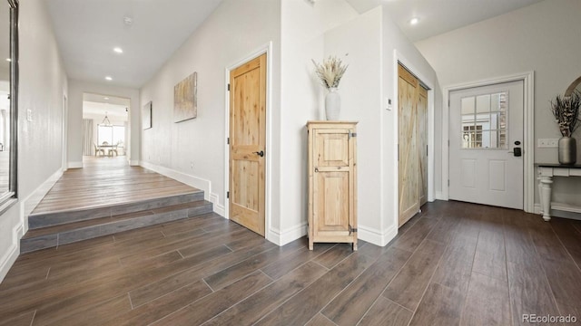 corridor with dark wood-style floors, recessed lighting, baseboards, and an inviting chandelier