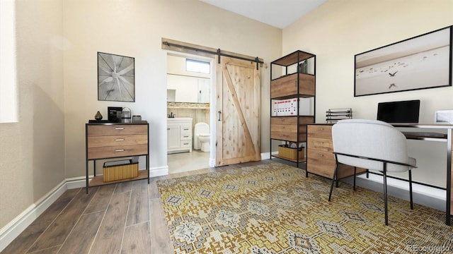 home office with a barn door, baseboards, and wood finished floors