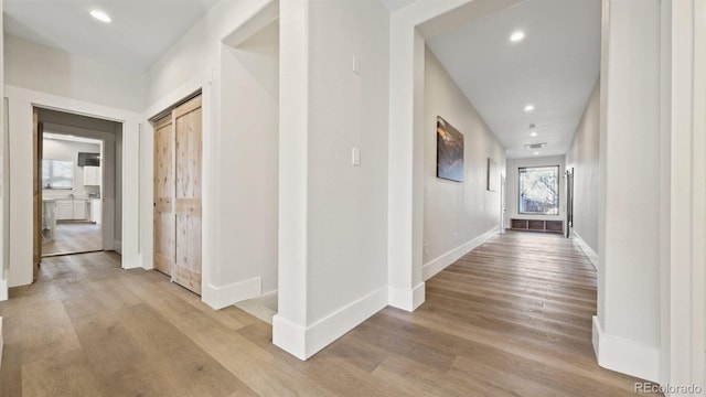 hallway featuring recessed lighting, light wood-type flooring, and baseboards