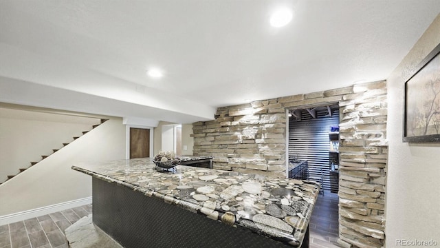 kitchen with stone countertops, baseboards, and wood finish floors