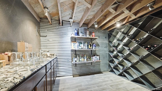 wine cellar featuring wood tiled floor, indoor wet bar, a textured wall, and a sink