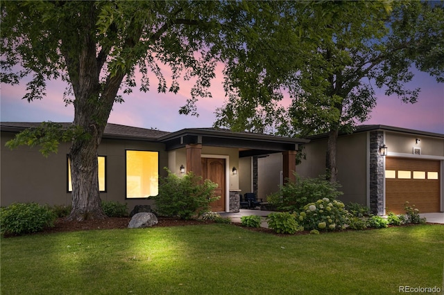 view of front of property with a garage, stone siding, a front yard, and stucco siding