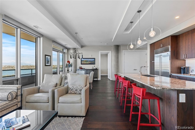 living room featuring a water view, dark wood-type flooring, and sink