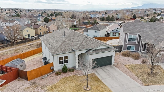 view of front of home featuring a shingled roof, fence private yard, a garage, a residential view, and driveway