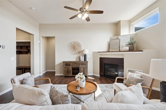 living room featuring baseboards, a tiled fireplace, and wood finished floors