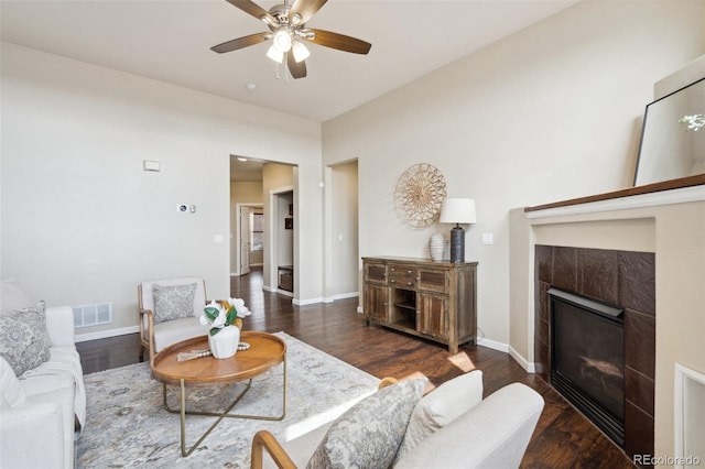 living room featuring visible vents, a fireplace, baseboards, and wood finished floors