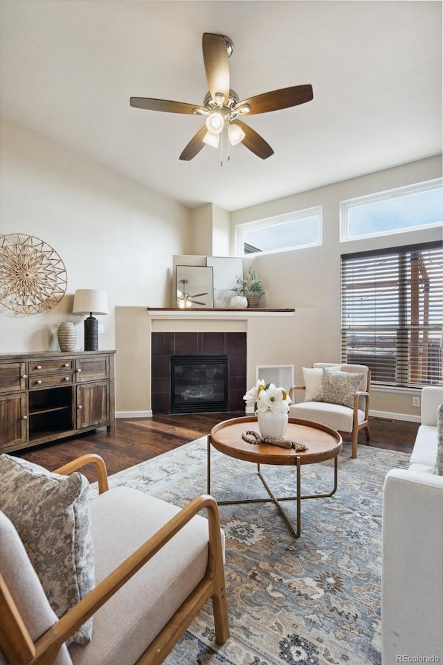 living area featuring baseboards, wood finished floors, and a tile fireplace