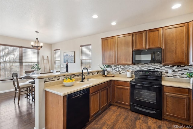 kitchen with backsplash, a sink, a peninsula, and black appliances