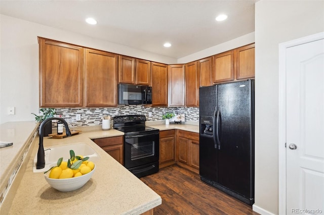 kitchen with brown cabinetry, light countertops, a sink, and black appliances