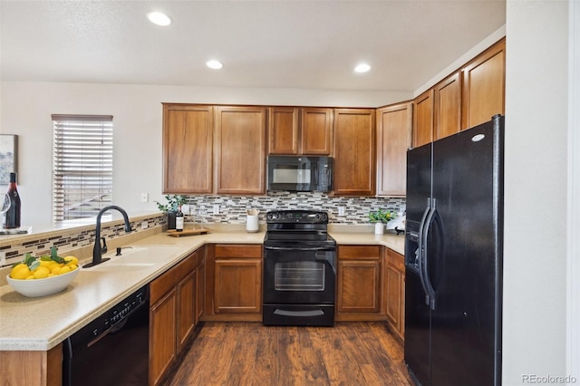 kitchen featuring brown cabinets, light countertops, a sink, and black appliances