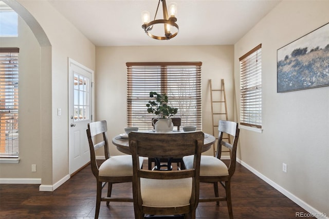 dining room featuring arched walkways, an inviting chandelier, wood finished floors, and baseboards