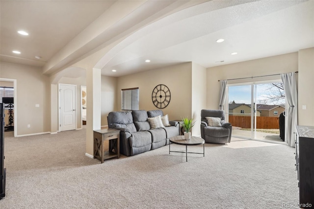 carpeted living room featuring arched walkways, baseboards, and recessed lighting