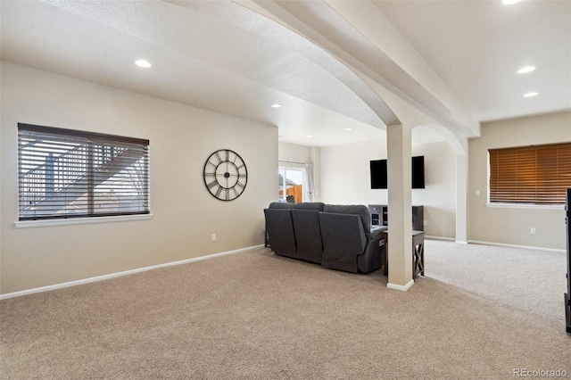 living area featuring recessed lighting, light carpet, arched walkways, and baseboards