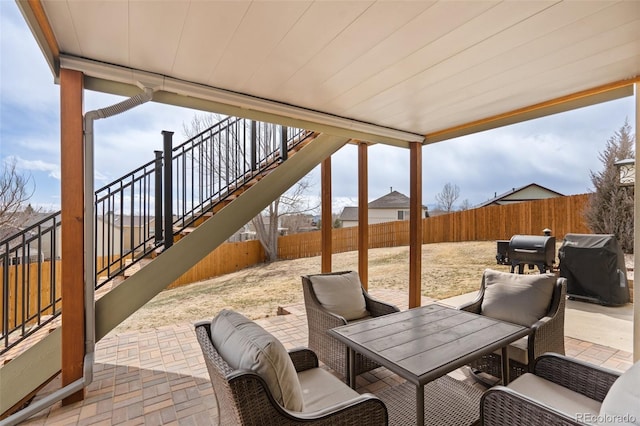 view of patio / terrace featuring outdoor dining area, a fenced backyard, stairway, and grilling area