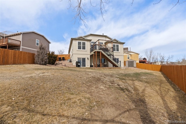 back of property featuring stucco siding, a fenced backyard, a wooden deck, and stairs