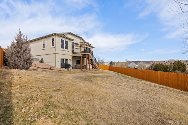 rear view of property featuring stucco siding, fence, a deck, and stairs