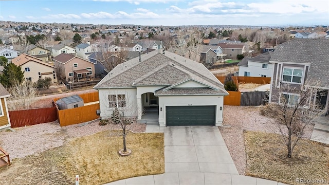 view of front of property featuring an attached garage, fence, driveway, roof with shingles, and a residential view