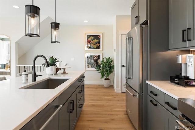 kitchen featuring gray cabinetry, sink, light hardwood / wood-style flooring, pendant lighting, and appliances with stainless steel finishes