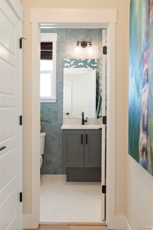 bathroom featuring vanity, toilet, and tile walls