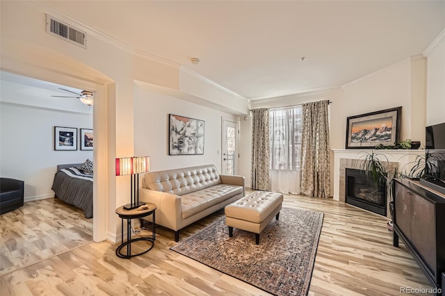 living room featuring ceiling fan, a fireplace, light hardwood / wood-style floors, and ornamental molding