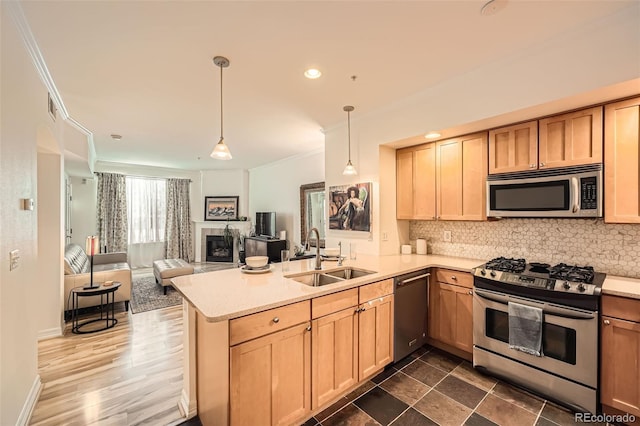 kitchen featuring light brown cabinets, hanging light fixtures, sink, appliances with stainless steel finishes, and kitchen peninsula