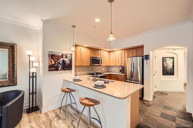 kitchen featuring pendant lighting, sink, decorative backsplash, appliances with stainless steel finishes, and kitchen peninsula