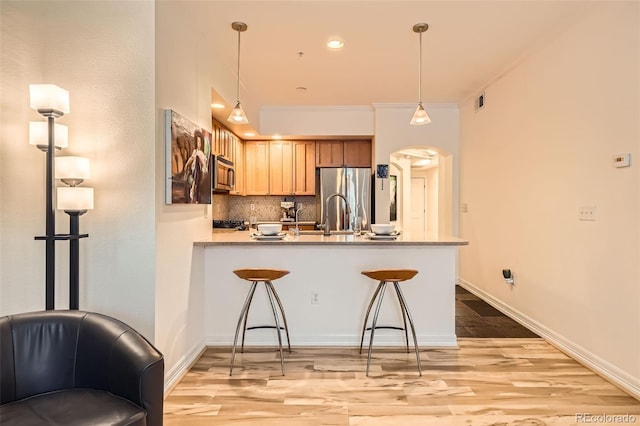 kitchen featuring stainless steel appliances, backsplash, kitchen peninsula, pendant lighting, and ornamental molding