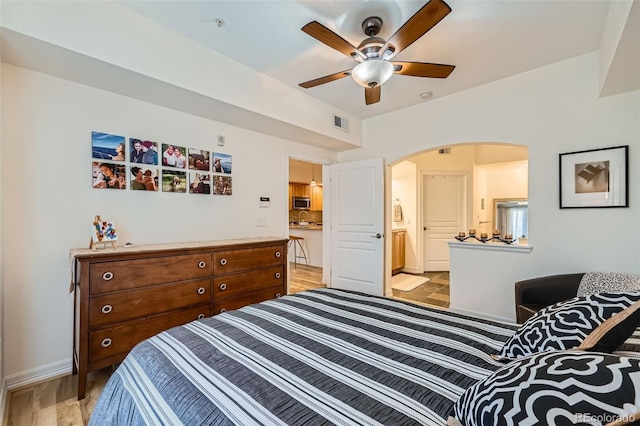 bedroom with ensuite bath, ceiling fan, and light wood-type flooring