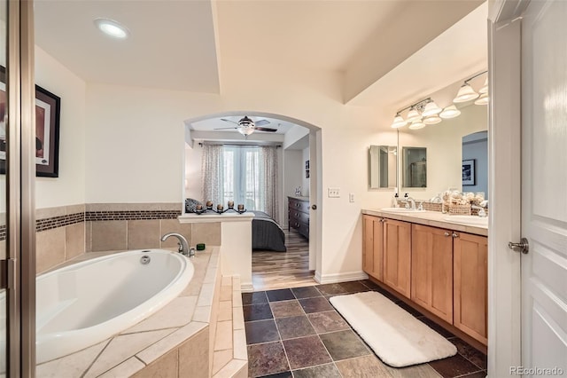 bathroom with tiled bath, ceiling fan, and vanity