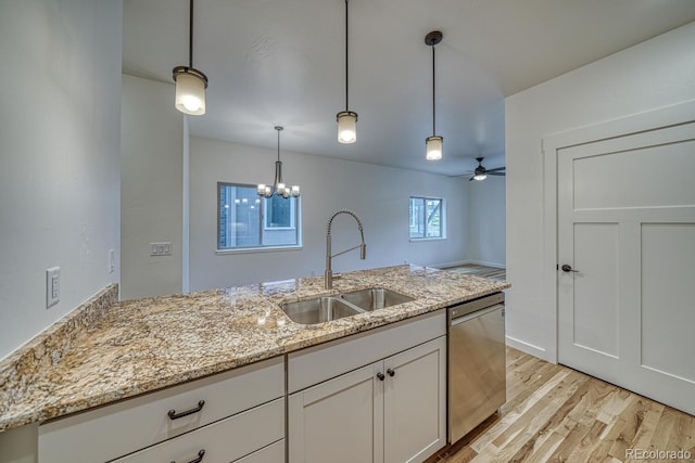 kitchen with stainless steel dishwasher, hanging light fixtures, sink, white cabinetry, and light stone countertops