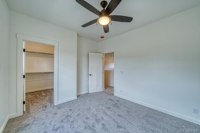 unfurnished bedroom with ceiling fan, light colored carpet, a closet, and a walk in closet