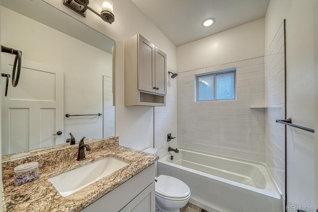 full bathroom featuring tiled shower / bath combo, vanity, and toilet