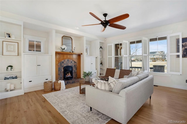 11776 Perry St, Westminster, CO 80031 - living area with a ceiling fan, a tiled fireplace, built in features, light wood-type flooring, and baseboards