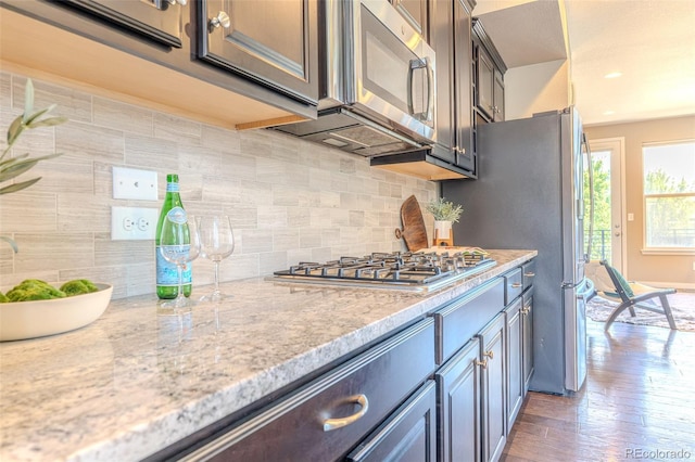 15738 E Broncos Pl, Englewood, CO 80112 - kitchen featuring appliances with stainless steel finishes, tasteful backsplash, light stone counters, and wood finished floors