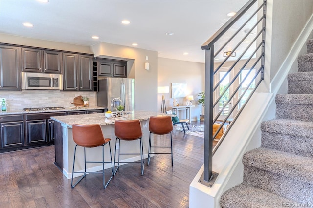15738 E Broncos Pl, Englewood, CO 80112 - kitchen with stainless steel appliances, an island with sink, dark wood-type flooring, a breakfast bar area, and recessed lighting