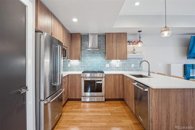 kitchen with a sink, wall chimney exhaust hood, light countertops, and stainless steel appliances