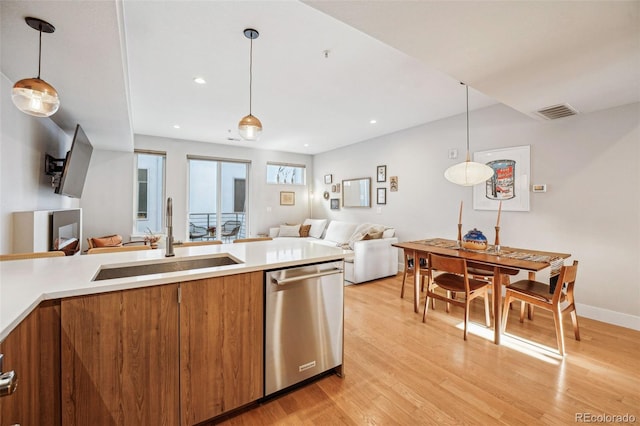 kitchen with sink, light wood-type flooring, dishwasher, and hanging light fixtures