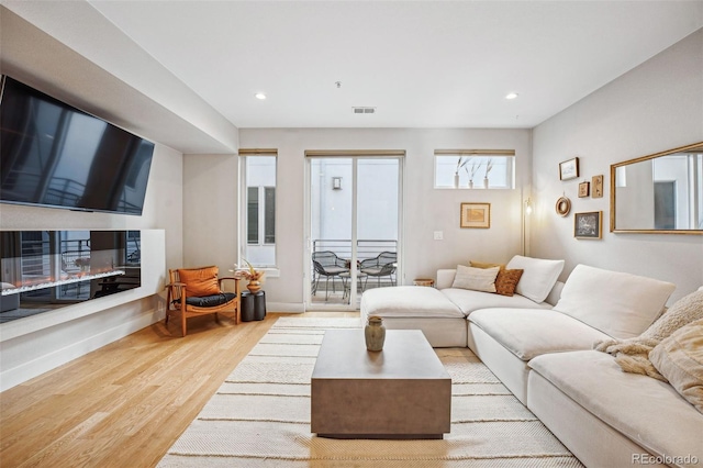 living room with baseboards, light wood-type flooring, visible vents, and recessed lighting