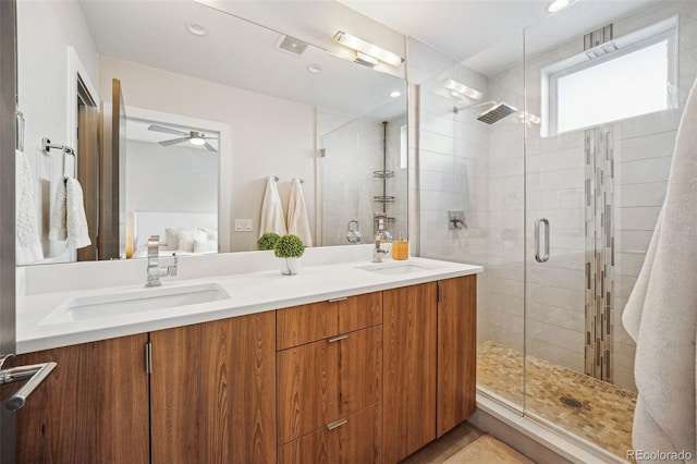 full bath featuring double vanity, a stall shower, a sink, and a ceiling fan