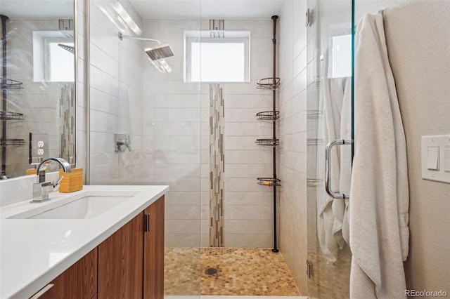 bathroom featuring plenty of natural light, a shower with shower door, and vanity