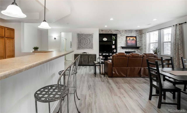 dining area with a stone fireplace and light hardwood / wood-style floors