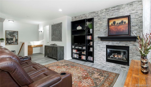 living room featuring hardwood / wood-style flooring, a stone fireplace, and built in shelves