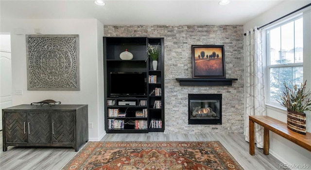 living room with a stone fireplace and light wood-type flooring